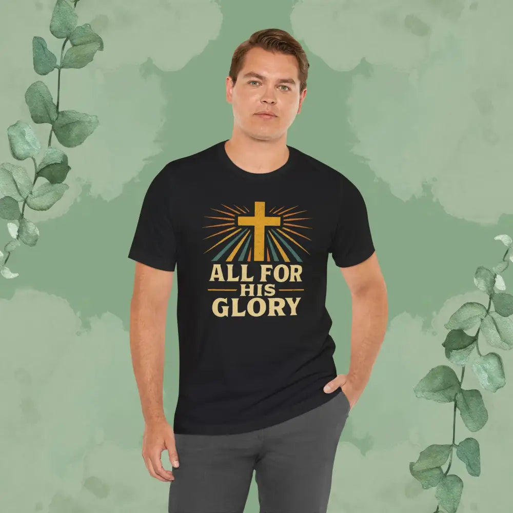 Man wearing a black t-shirt with 'All for His Glory' design on a green leafy background