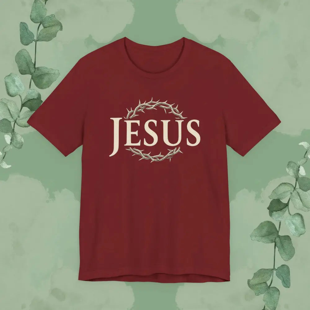Red t-shirt with 'JESUS' printed on it against a green leafy background