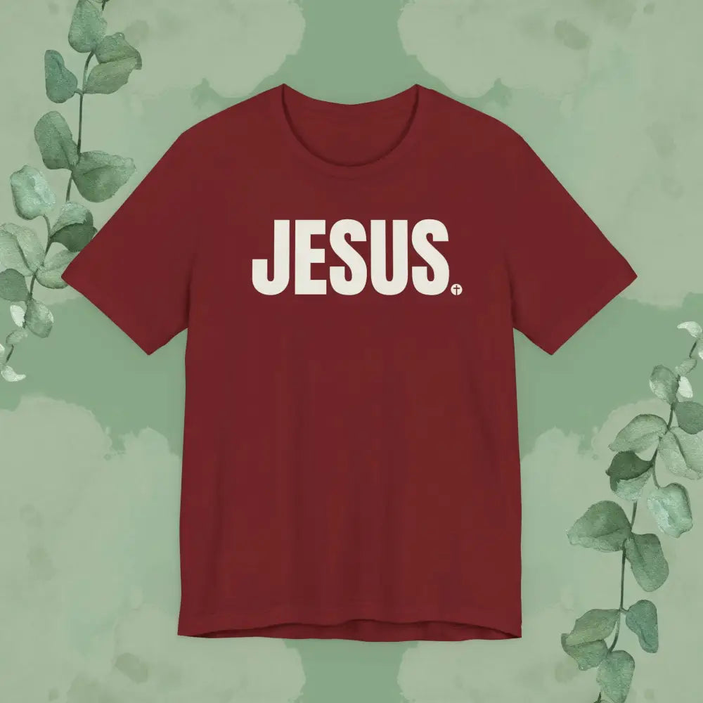 Red t-shirt with 'JESUS' printed on it against a green leafy background