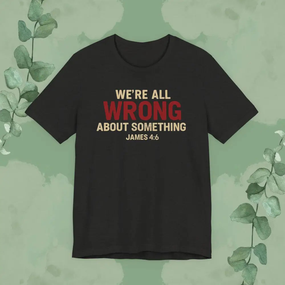 Black heather t-shirt with text 'WE'RE ALL WRONG ABOUT SOMETHING JAMES 4:6' on a green background with leaves.