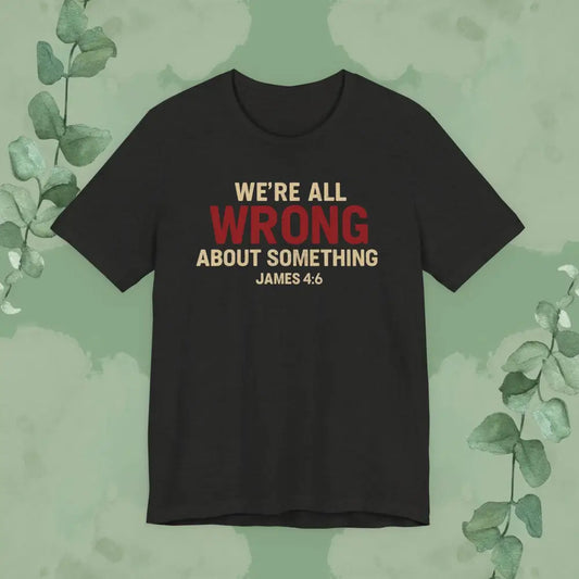 Black heather t-shirt with text 'WE'RE ALL WRONG ABOUT SOMETHING JAMES 4:6' on a green background with leaves.