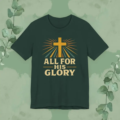 Dark green t-shirt with a cross and 'All for His Glory' text on a green background with eucalyptus leaves.